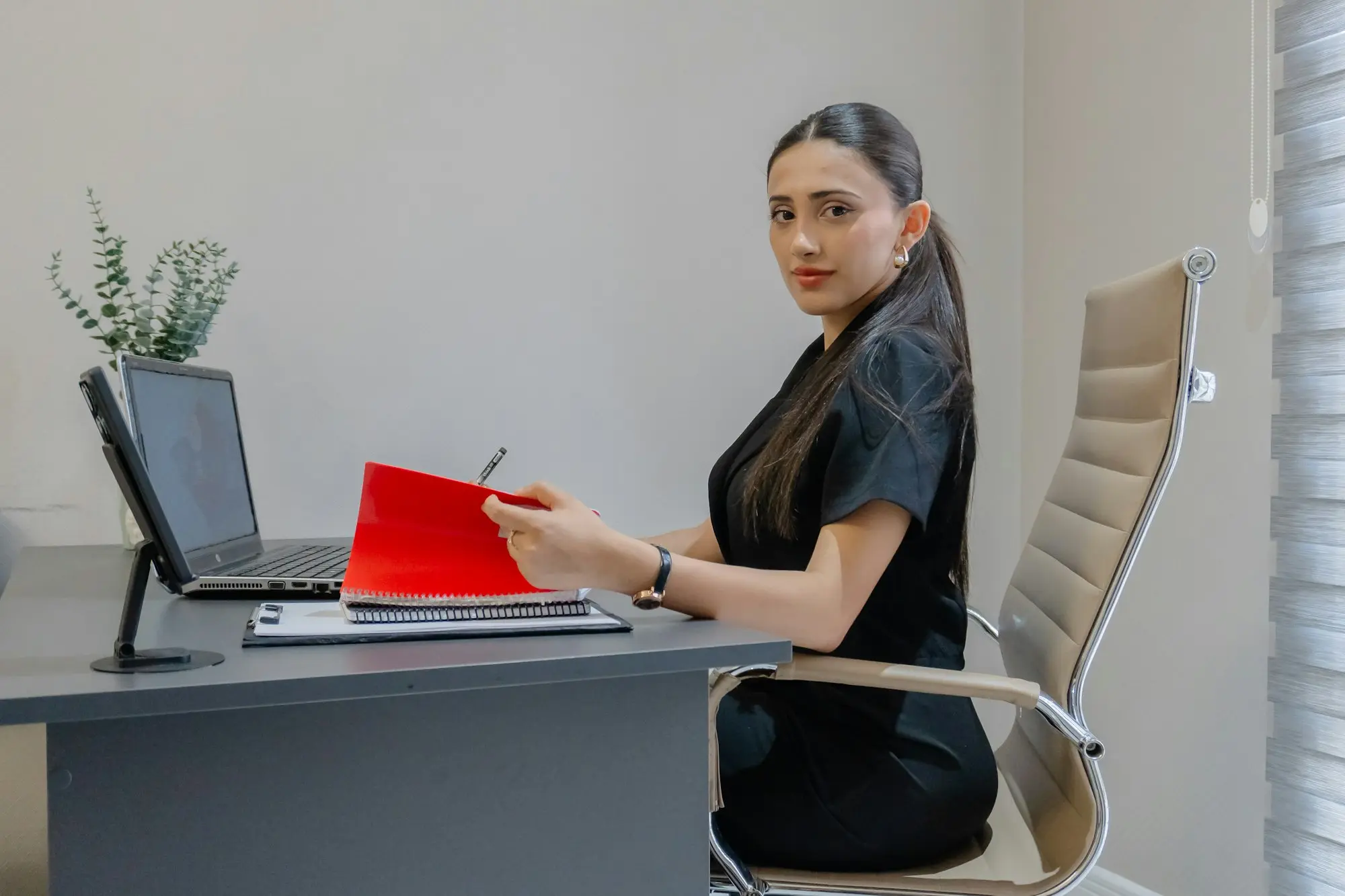 Woman at her desk with a laptop and a red folder