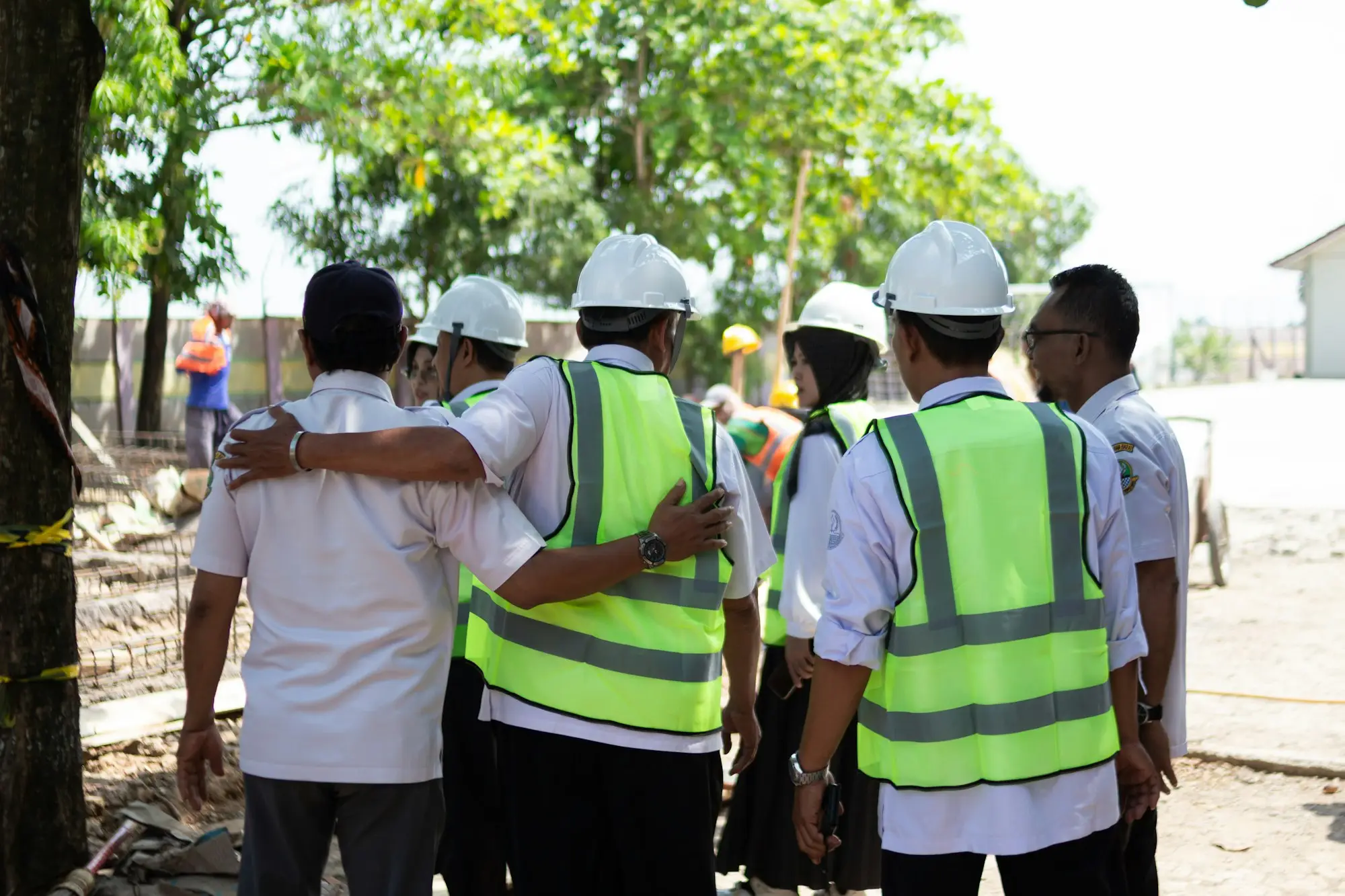Construction workers in hard hats and vests reviewing plans